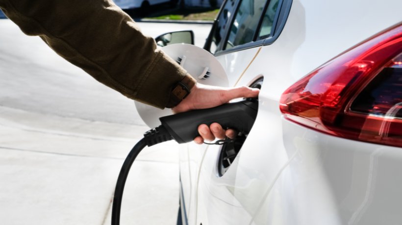 Someone hooking up an electric car with a charger